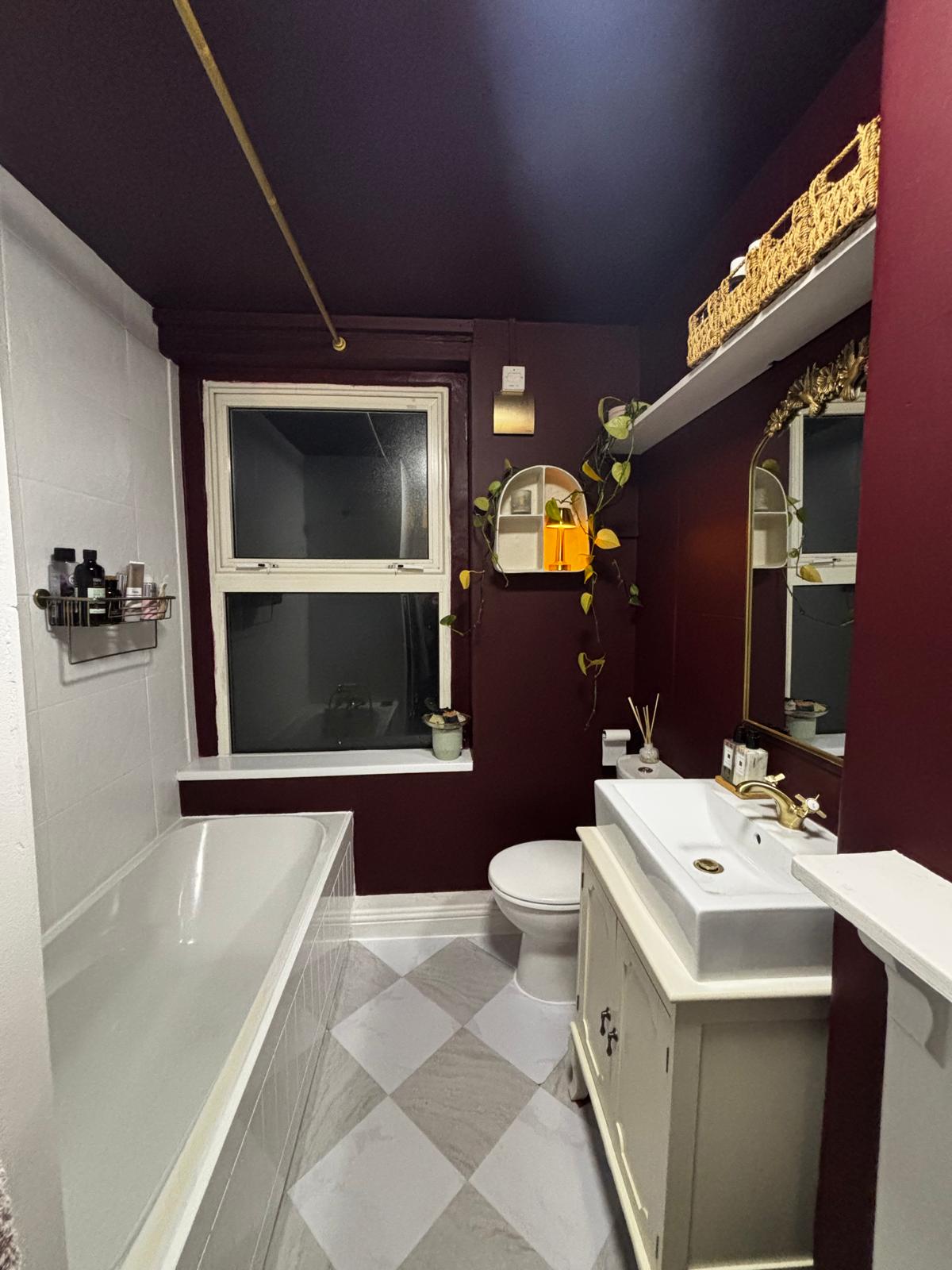 After: the same bathroom decorated in deep burgundy with a new vanity unit and chequerboard tiled floor.