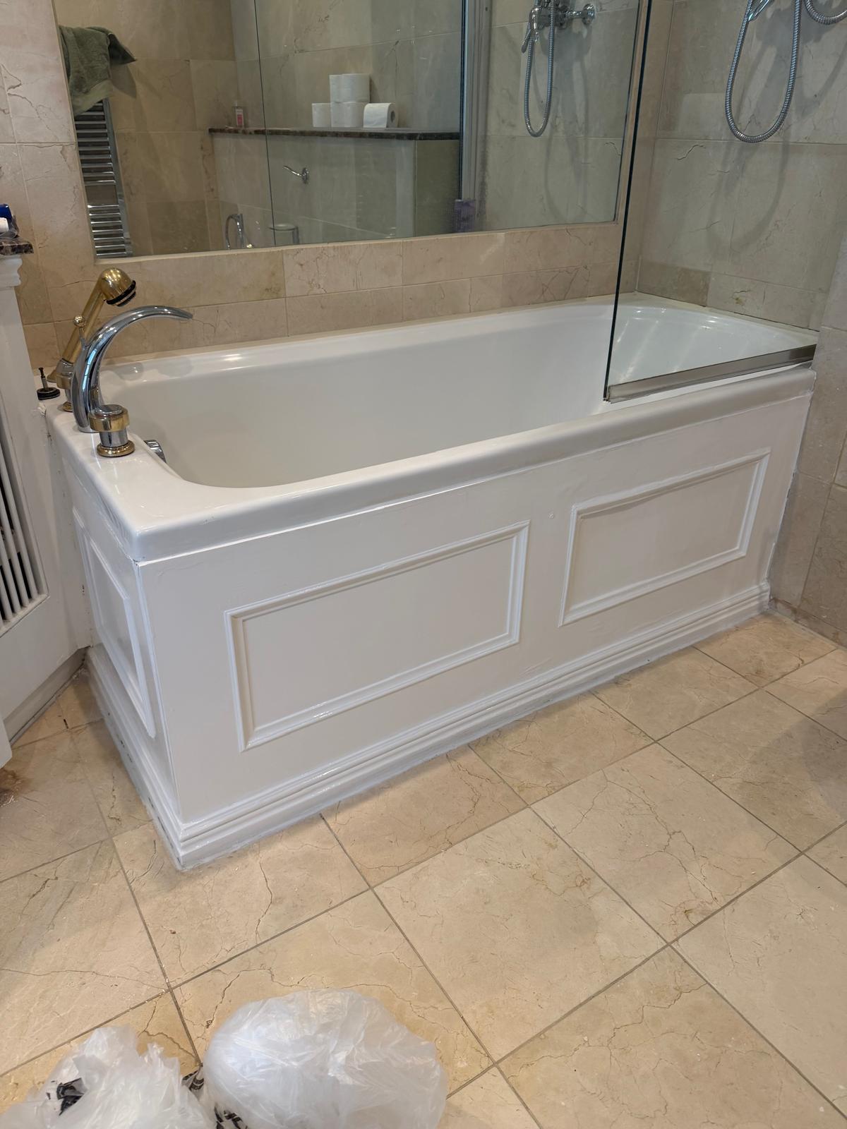 A white bathtub with a decorative side panel in a tiled bathroom.