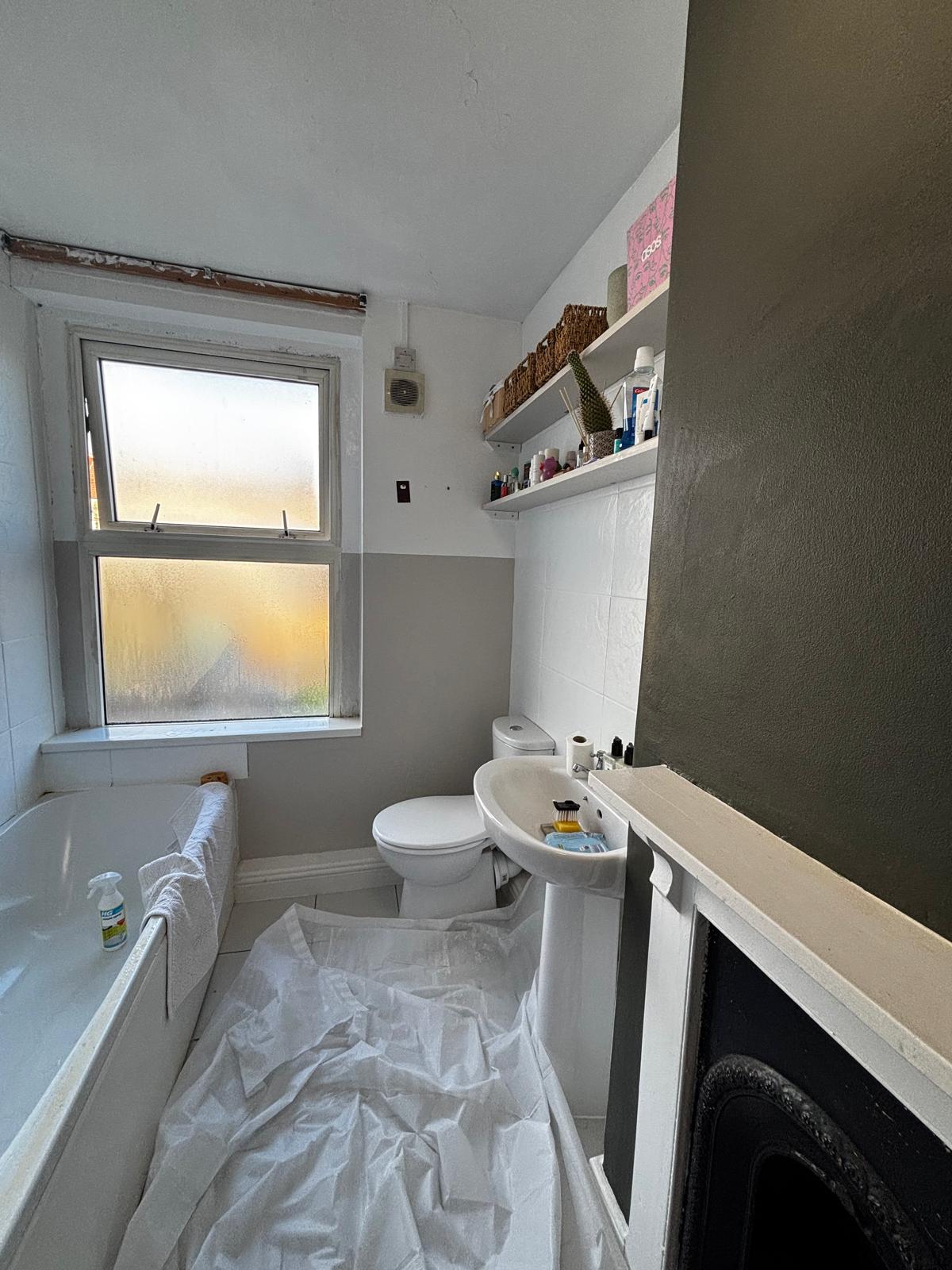 Before: dated bathroom with white and grey painted walls and an old basin.