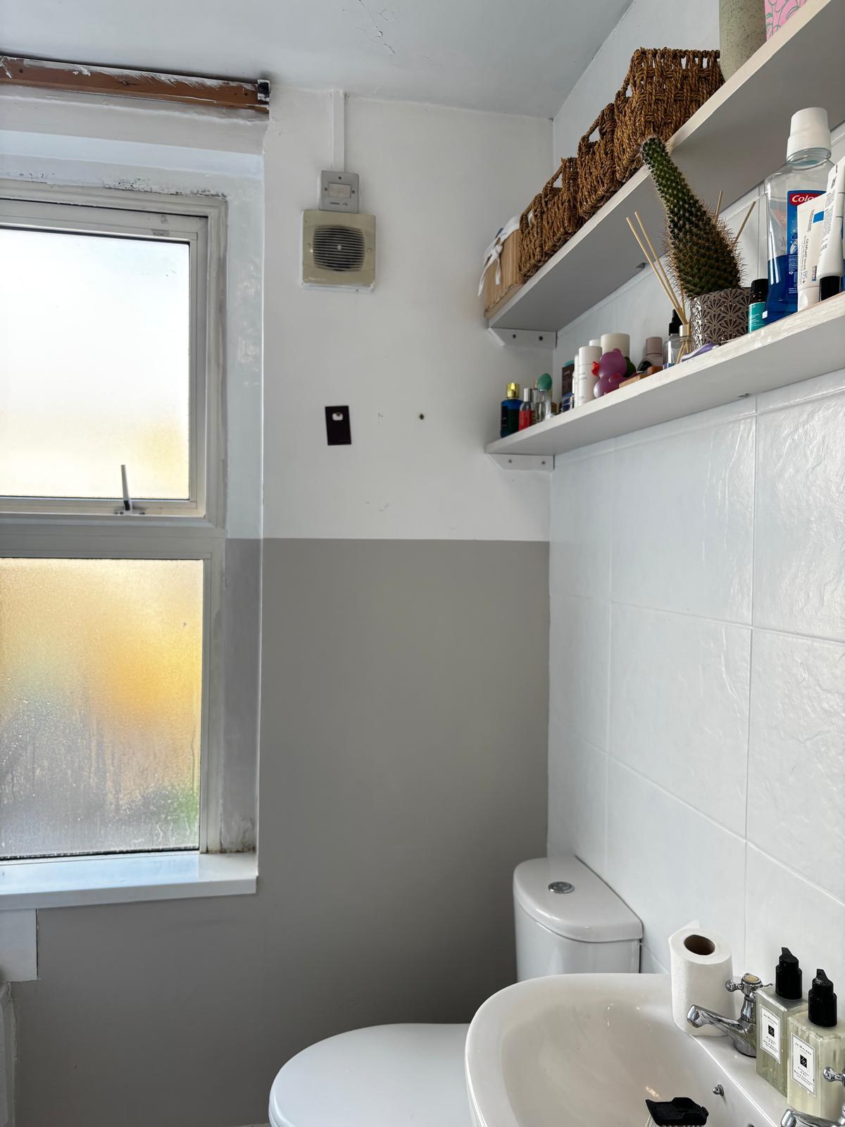 Before: bathroom with white walls, a window and open shelving before work started.