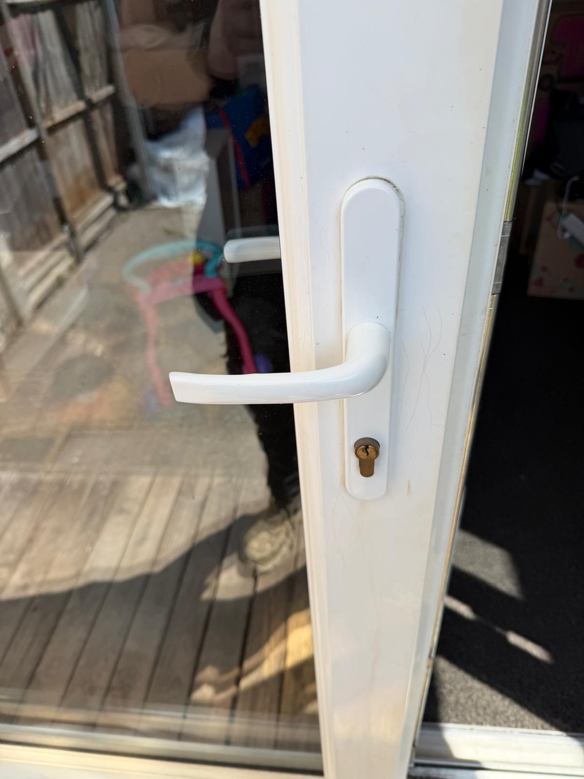 A white uPVC door handle with a gold lock cylinder.