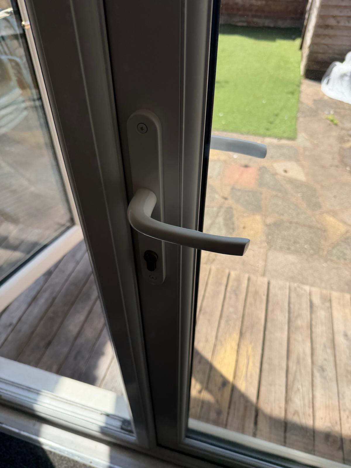 A white door handle and lock fitted to a glass door.
