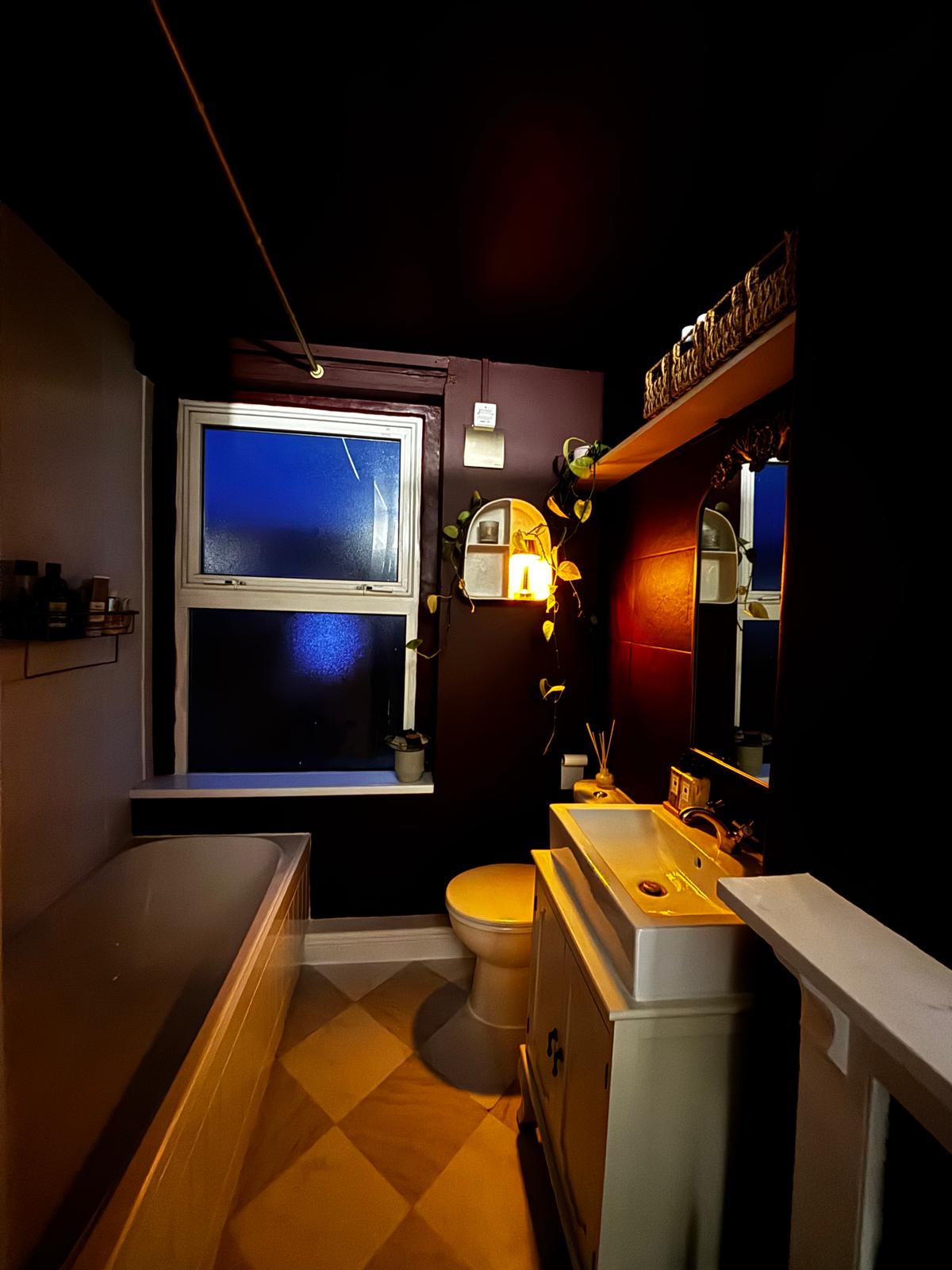 A finished bathroom with dark walls, gold fittings and a chequerboard floor.