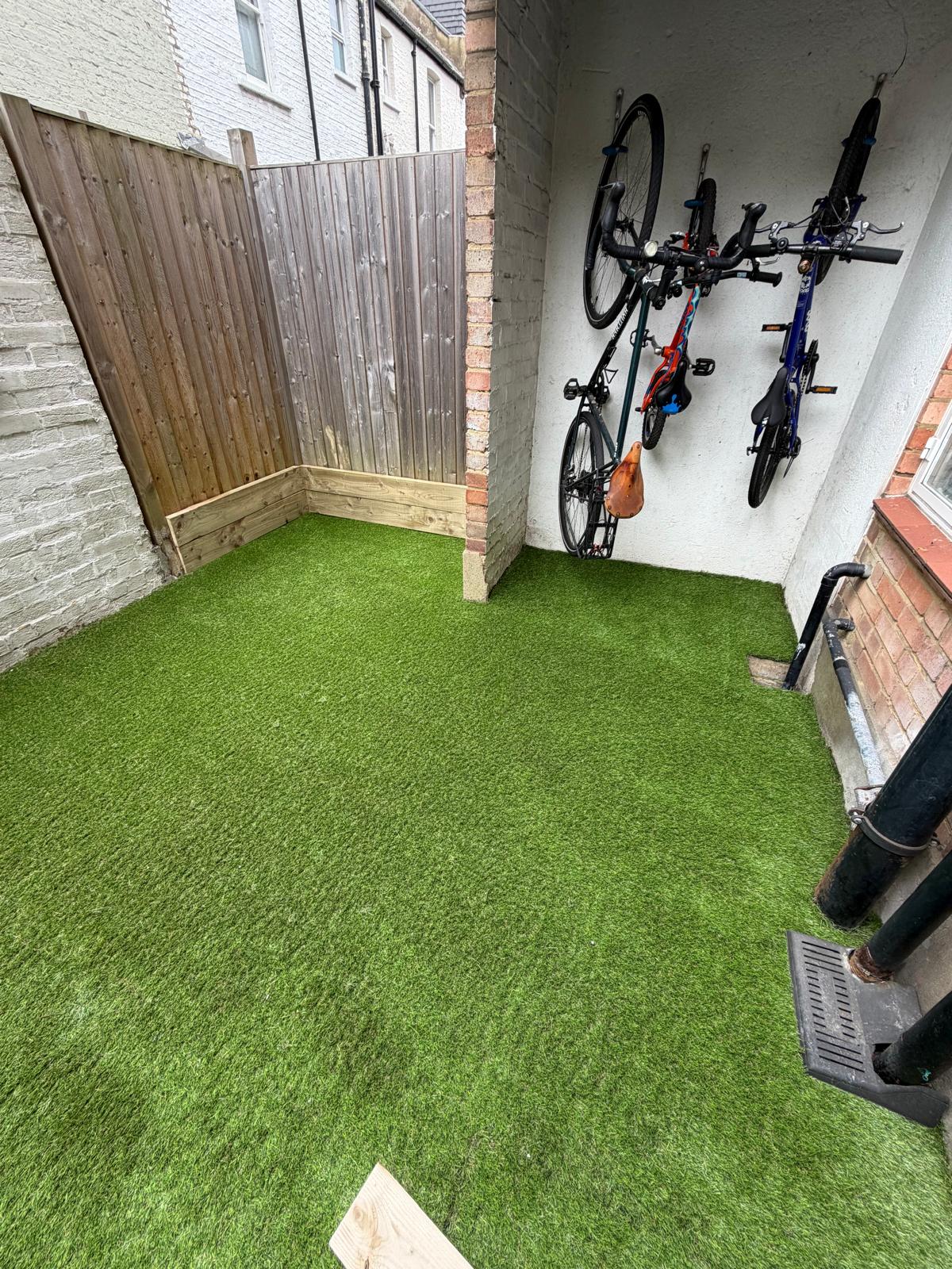 A small courtyard with freshly laid artificial grass.