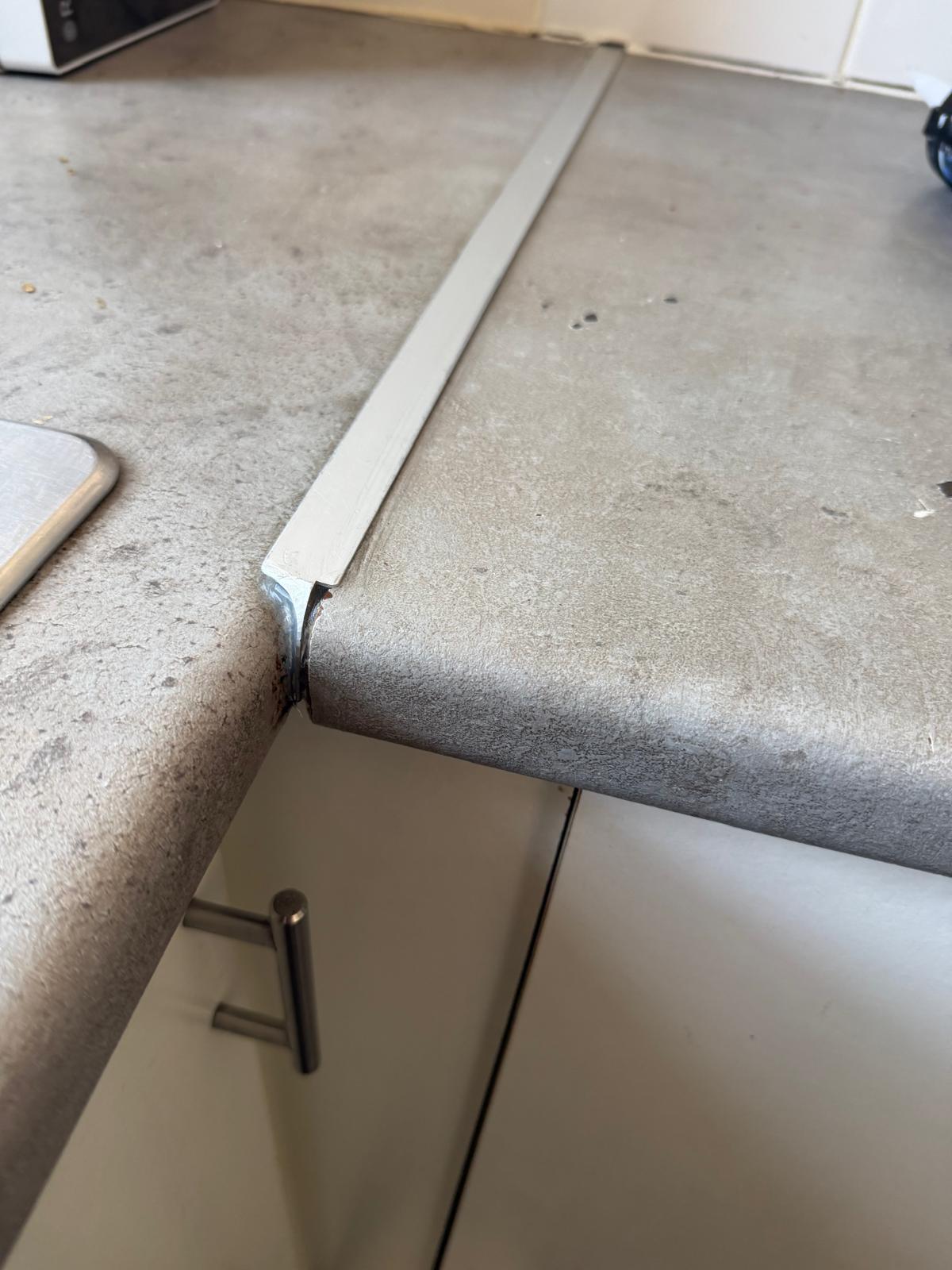 A close-up of the joint between two grey kitchen worktop sections.