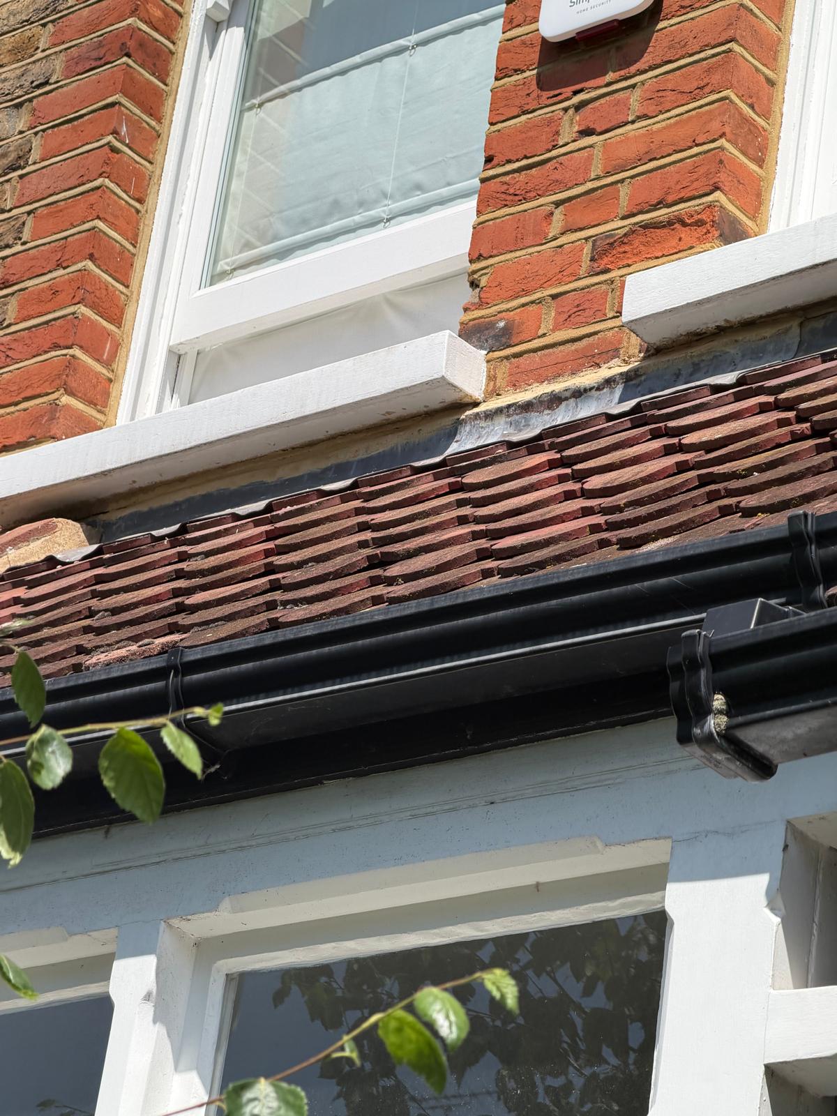 Red roof tiles and black guttering on a brick building.