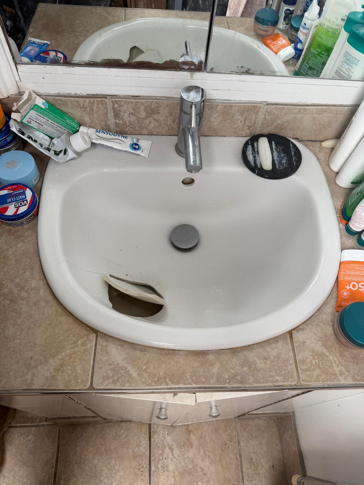 An old cracked white porcelain basin before removal.