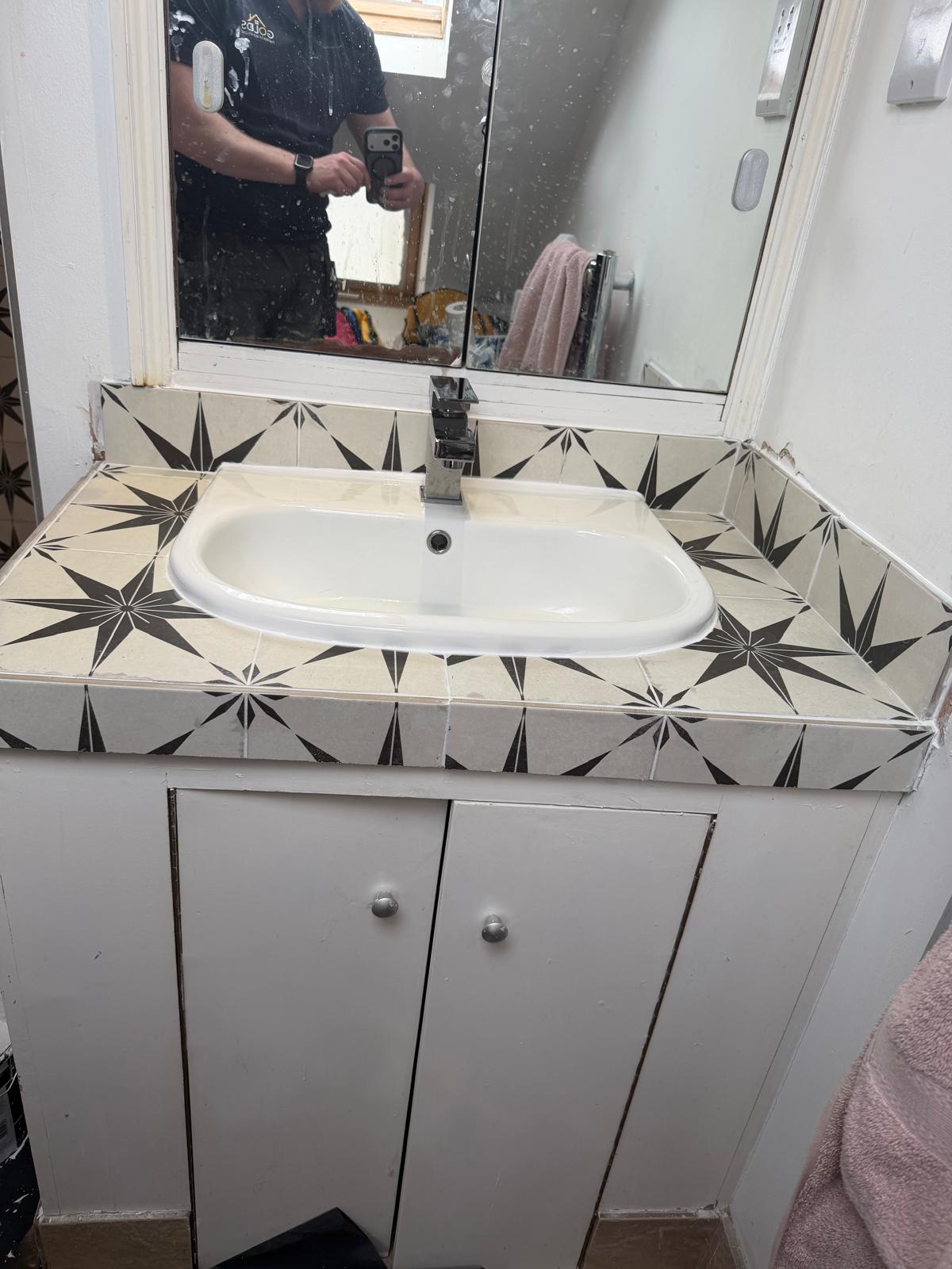 A newly fitted white basin with taps in a bathroom.