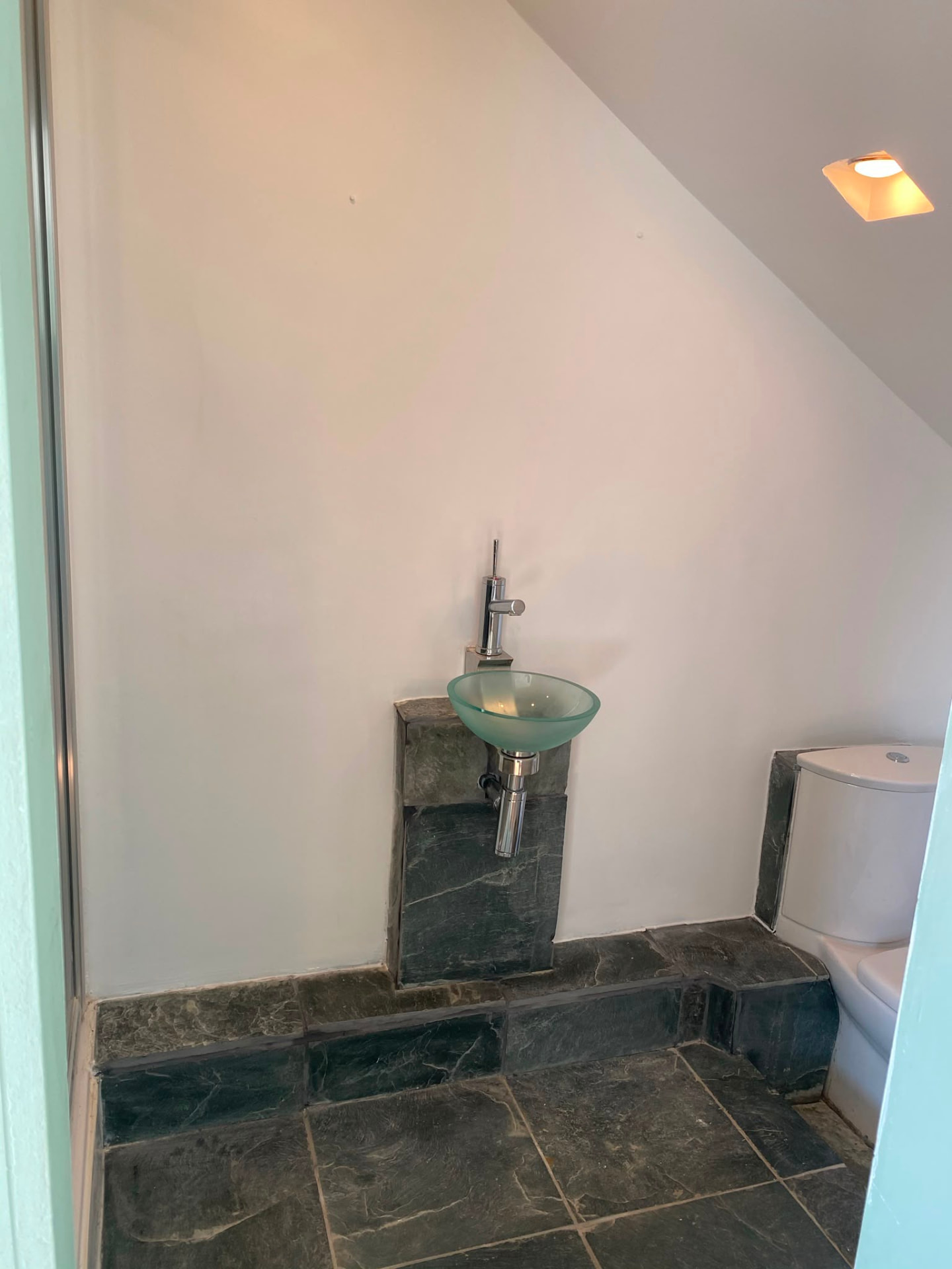 After: the finished bathroom corner with smooth white walls and a glass bowl basin.