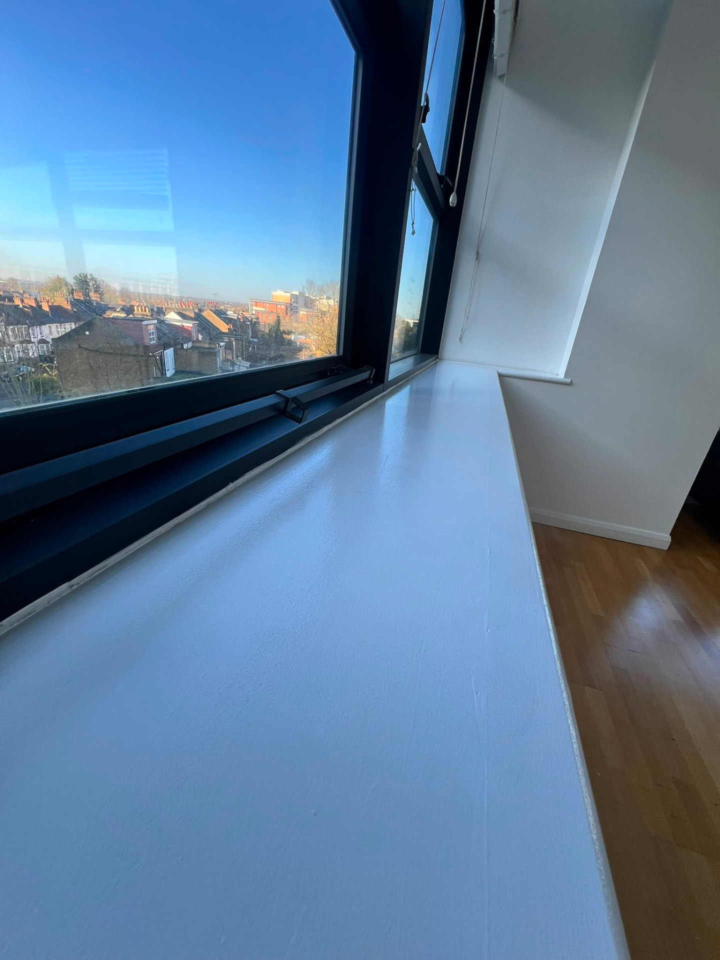 After: the same windowsill repaired and repainted in a smooth white finish.